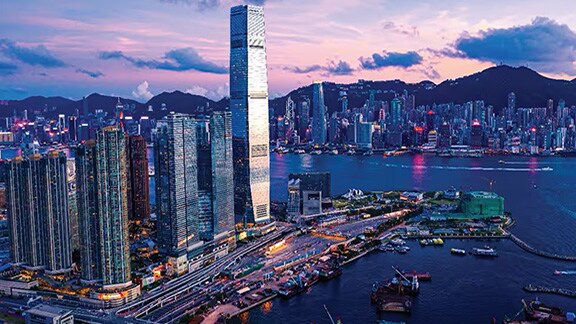 Aerial view of a city lit up at dusk, along the banks of a river