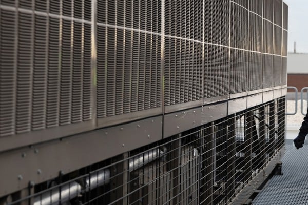 Person inspecting rooftop HVAC equipment at a commercial building.