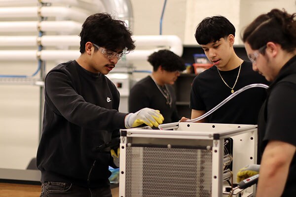 Students at Waukegan High School practice technical skills on a residential HVAC unit