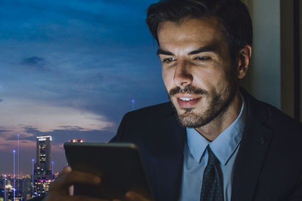 Close-up of a man using a tablet, with the cityscape in the background