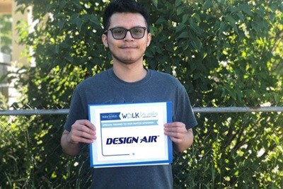Miguel, an adolescent boy holding up a 'Design Air' sign in blue