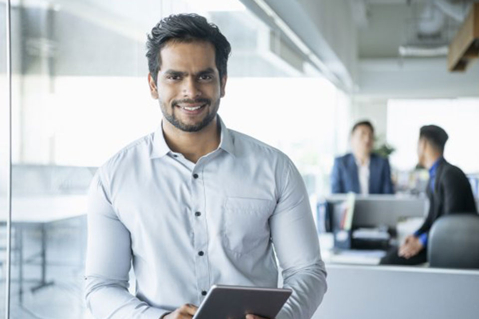 A man looking at the camera and holding a tablet