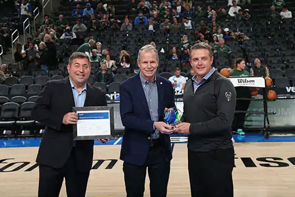 Johnson Controls CEO George Oliver (center) presents “Blueprint of the Future” award to Milwaukee Bucks and Fiserv Forum President Peter Feigin (left) and SVP and GM Dennis Williams