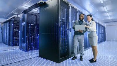 A man and a woman standing in a hub room and looking at a laptop