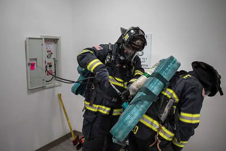 A firefighter assisting another firefighter with equipment