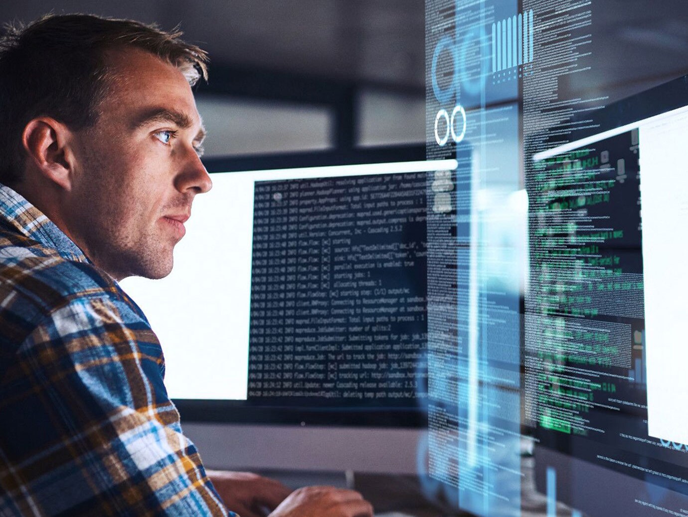 Man working on codes on a desktop with two screens and a holographic screen open