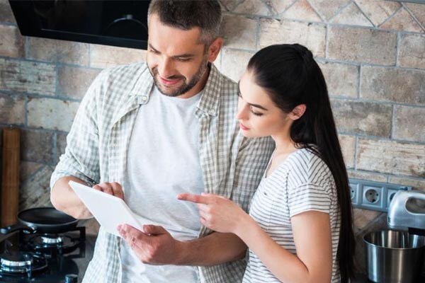 couple in a kitchen looking at a tab