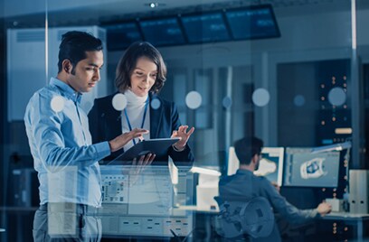 A man and a woman working on a tablet inside an office