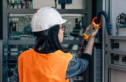 A woman in a safety helmet using a digital multimeter