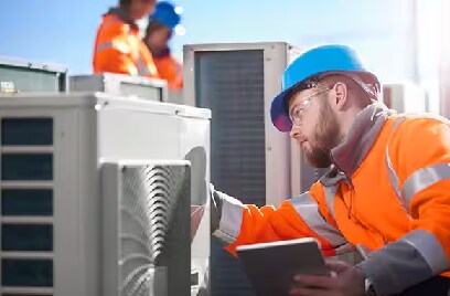 Man in safety gear inspecting outdoor fans on a rooftop