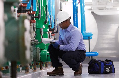 Man in Johnson Controls safety gear inspecting a piping system