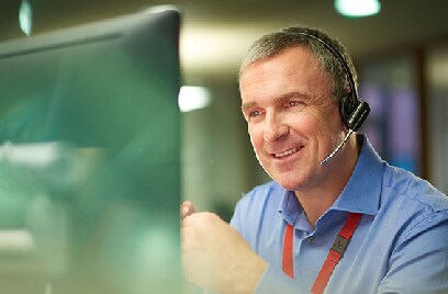 Man wearing headphones with a microphone sitting in front of a computer