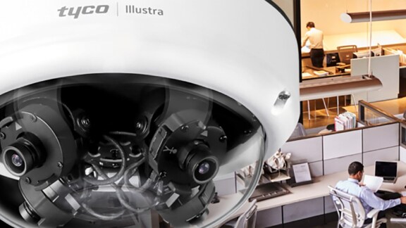 Close-up of a Tyco Illustra video surveillance camera overlooking a workspace in office