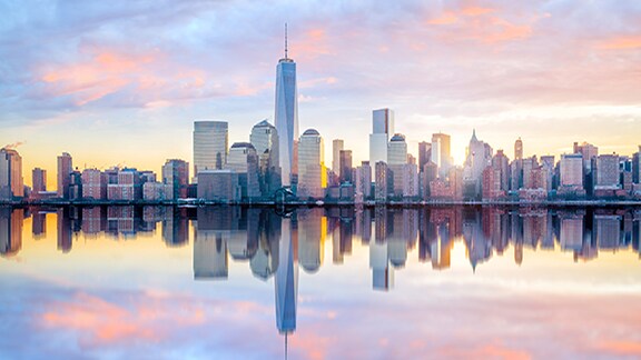 An urban skyline by a water body, at sunset