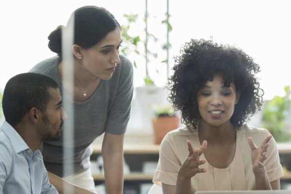 Three employees having a discussion in an office room