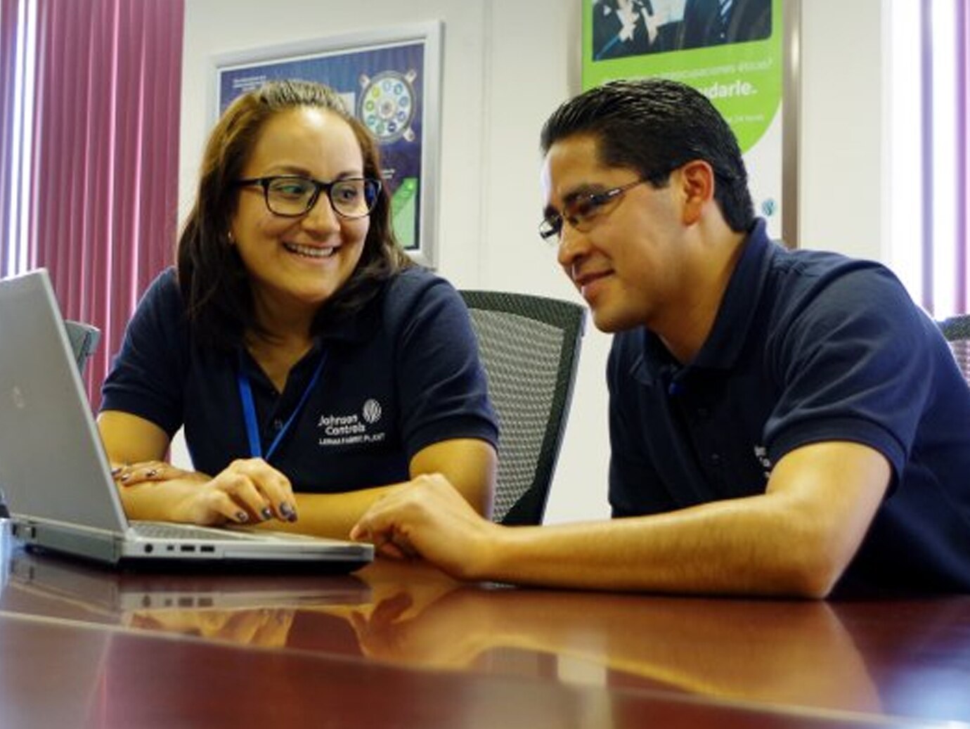 Two Johnson Controls employees sitting at a conference table with a laptop open in front of them